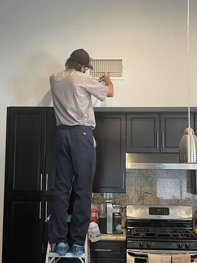 Technician inspecting an air vent during HVAC service in Hampton